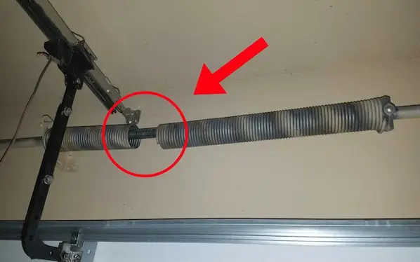 Close-up of a broken garage door torsion spring with visible gap in Durham NC
